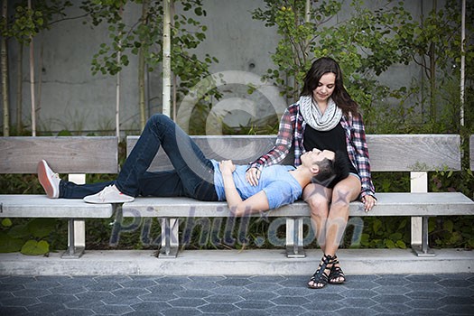 Romantic interracial young couple relaxing on park bench outside