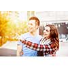 Romantic interracial young couple standing together pointing outside in sunset light with intentional lens flare