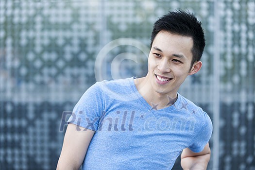 Portrait of confident young asian man smiling in urban environment with copy space