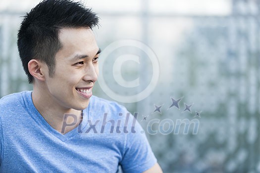 Portrait of confident young asian man in profile smiling on blue background with copy space