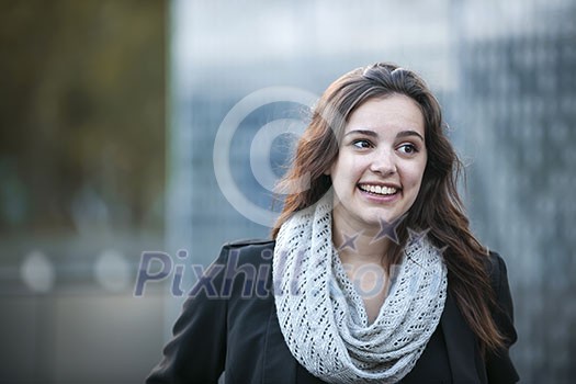 Candid portrait of happy young brunette woman smiling with copy space in urban setting