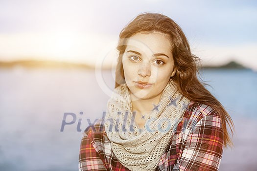 Portrait of young brunette woman near water looking at camera with copy space