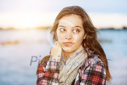 Candid portrait of young brunette woman at sunset looking away with copy space