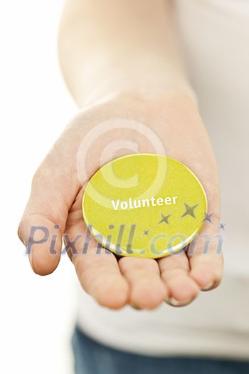 Closeup on female hand holding green volunteer button Closeup on female hand holding green volunteer button