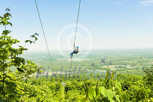 Young woman zip-lining with aerial countryside view at Blue Mountains, Ontario, Canada.