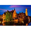 Famous view of Bruges - Rozenhoedkaai with Belfry and old houses along canal with tree in the night. Brugge, Belgium