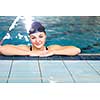 Female swimmer in an indoor swimming pool - looking at the camera, smiling wholeheartedly (shallow DOF; color toned image)