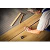 DIY, repair, building and home concept - close up of male hands lying parquet floor board/laminate flooring (shallow DOF; color toned image)