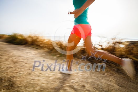 Young woman on her evening jog along the seacoast (motion blurred image)