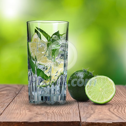mohito cocktail with lime on wooden table against green natural background