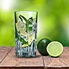 mohito cocktail with lime on wooden table against green natural background