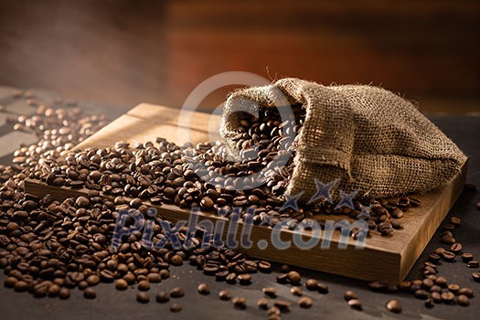spilled coffee beans in bag on wooden table. Morning light spilled coffee beans in bag on wooden table. Morning light