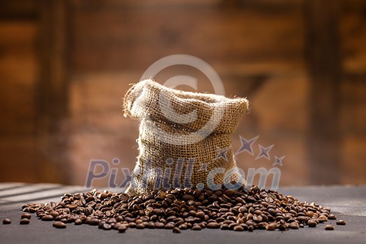 coffee beans with steam in bag on black table against wooden background coffee beans with steam in bag on black table against wooden background