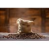 coffee beans with steam in bag on black table against wooden background