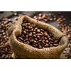 spilled coffee beans in bag on wooden table. Morning light