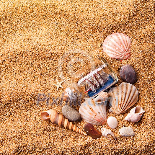 background of various shells and small ship in bottle on sand. Top view