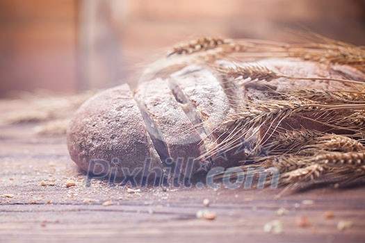 Bread and wheat on wooden table, shallow DOF, raw image