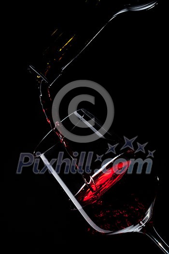 red wine pouring into wine glass isolated on black red wine pouring into wine glass isolated on black