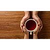 Womans and mens hands holding hot cup of tea on wooden table. Header for website