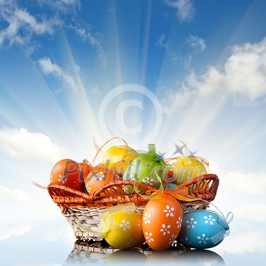 color easter eggs in basket against blue sky and clouds