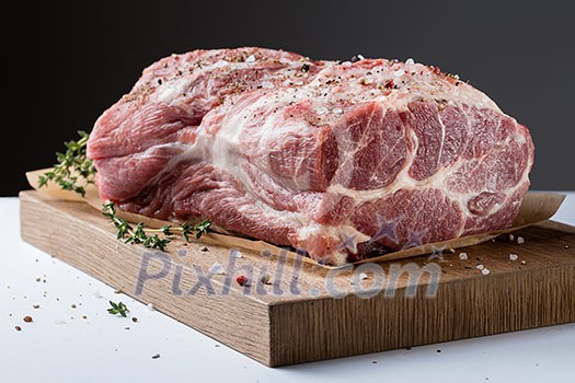 Photo of raw meat. Pork neck with herbs and green thyme on wooden board Photo of raw meat. Pork neck with herbs and green thyme on wooden board