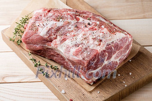 Photo of raw meat. Pork neck with herbs and green thyme on wooden board. Top view