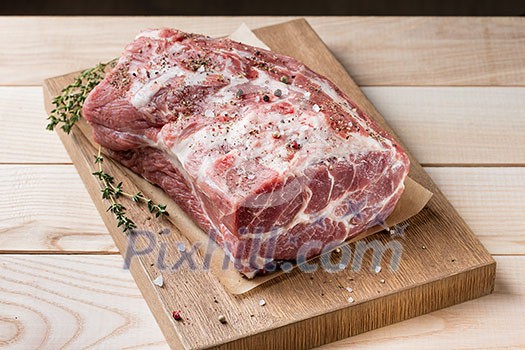 Photo of raw meat. Pork neck with herbs and green thyme on wooden board. Top view Photo of raw meat. Pork neck with herbs and green thyme on wooden board. Top view