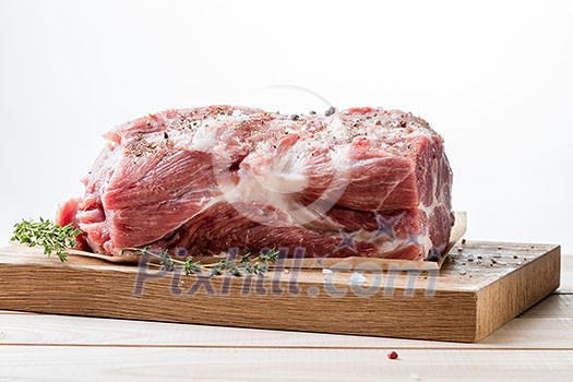 Photo of raw meat. Pork neck with herbs and green thyme on wooden board Photo of raw meat. Pork neck with herbs and green thyme on wooden board