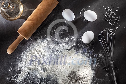 flour and ingredients on black table. Top view