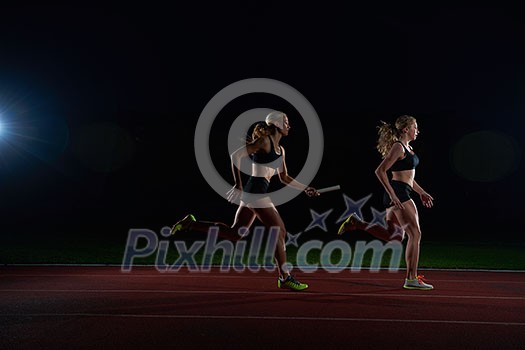woman athletic runners passing baton in relay race woman athletic runners passing baton in relay race