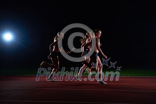 woman athletic runners passing baton in relay race woman athletic runners passing baton in relay race