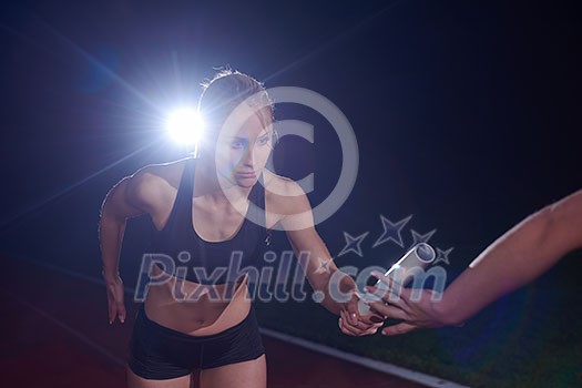 woman athletic runners passing baton in relay race woman athletic runners passing baton in relay race