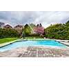 Backyard of residential house in spring with large pool and paved patio