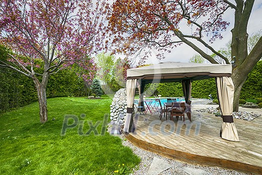 Backyard of residential house in spring with wooden deck and gazebo Backyard of residential house in spring with wooden deck and gazebo