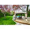 Backyard of residential house in spring with wooden deck and gazebo