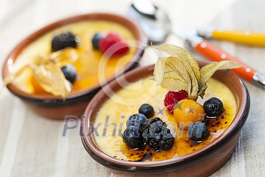 Sweet creme brulee desserts topped with fresh berries Sweet creme brulee desserts topped with fresh berries
