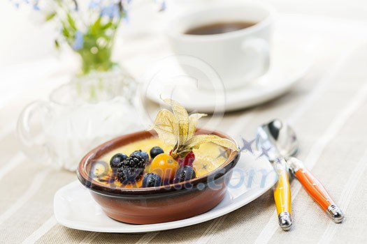 Sweet creme brulee dessert topped with fresh berries and coffee