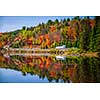 Tour bus driving though fall forest with colorful autumn leaves reflecting in lake. Highway 60 at Lake of Two Rivers, Algonquin Park, Ontario, Canada.