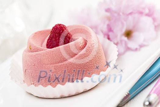 Closeup of pink raspberry mousse dessert with cherry blossom