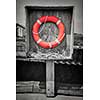 Orange life saver or buoy hanging in wooden box on dock. Prince Edward Island, Canada, selective coloring.
