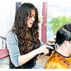 Hairdresser cutting hair in her salon with trimmer