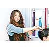 Happy hairstylist cutting hair in her salon