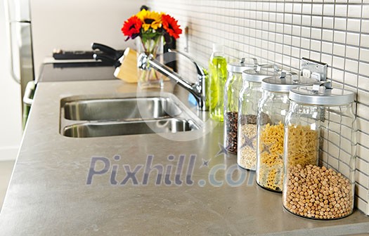 Modern small kitchen interior with glass jars on natural stone countertop Modern small kitchen interior with glass jars on natural stone countertop