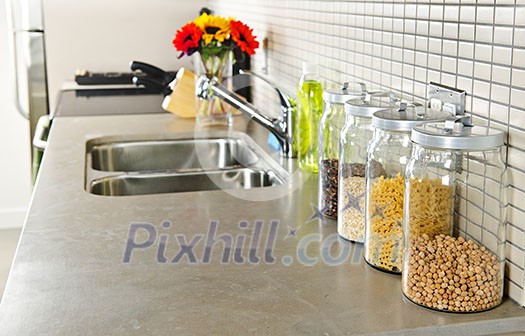 Modern small kitchen interior with glass jars on natural stone countertop