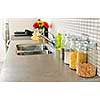 Modern small kitchen interior with glass jars on natural stone countertop