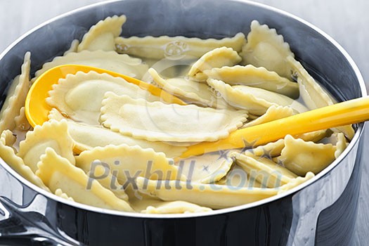 Cooking and stirring pot of ravioli pasta in boiling water Cooking and stirring pot of ravioli pasta in boiling water