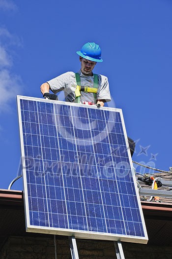 Man installing alternative energy photovoltaic solar panels on roof Man installing alternative energy photovoltaic solar panels on roof