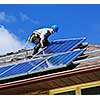 Man installing alternative energy photovoltaic solar panels on roof