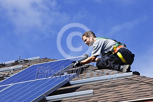 Man installing alternative energy photovoltaic solar panels on roof Man installing alternative energy photovoltaic solar panels on roof