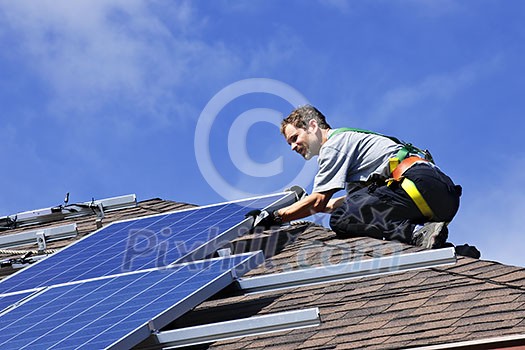 Man installing alternative energy photovoltaic solar panels on roof